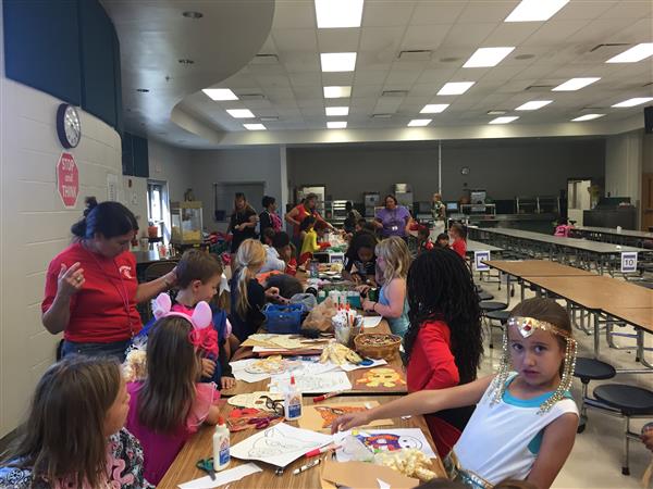 students sitting at long table draw and paint